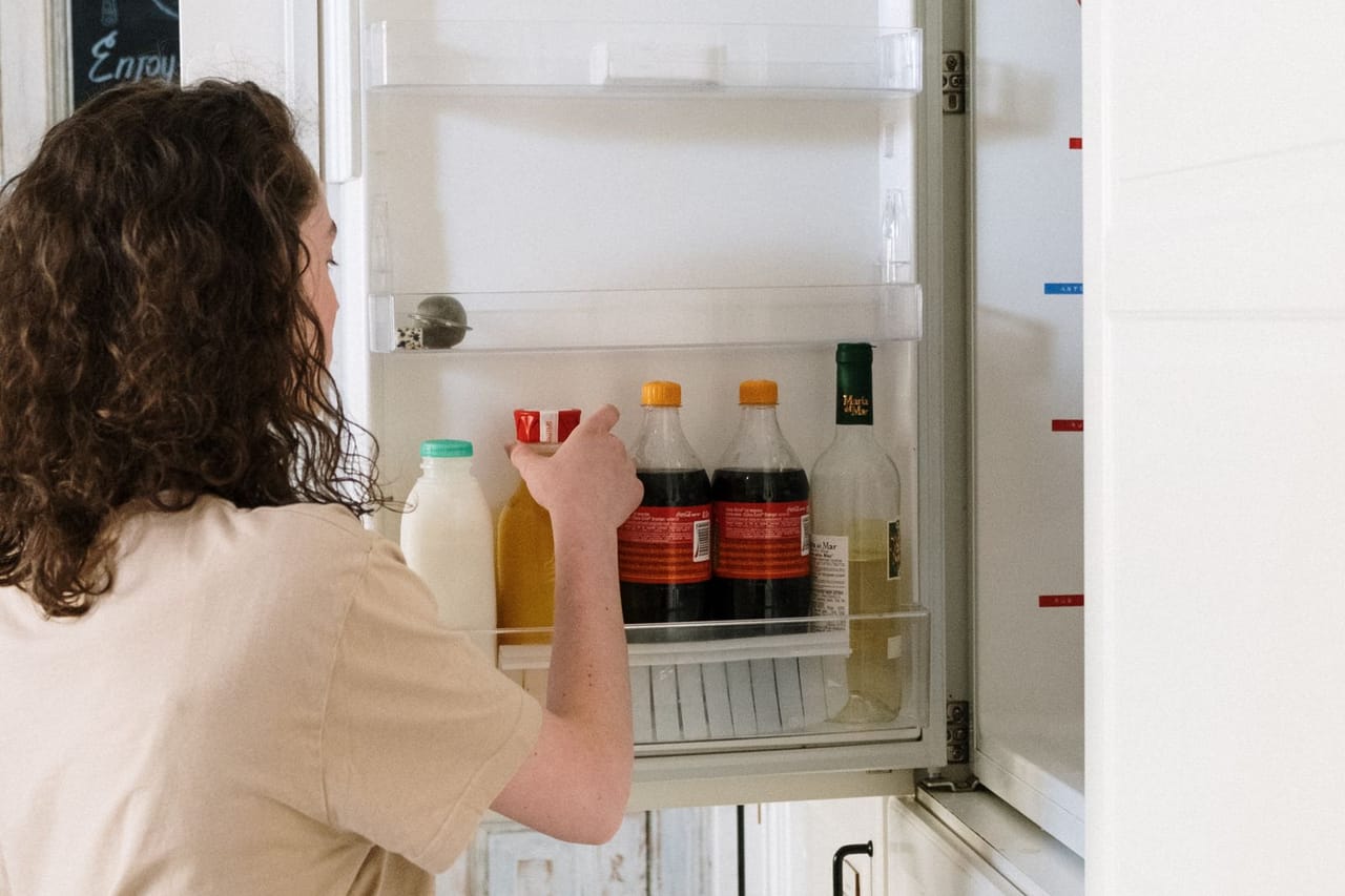 Appliance repair Brentwood TN: Woman in beige shirt holding bottle in the refrigerator