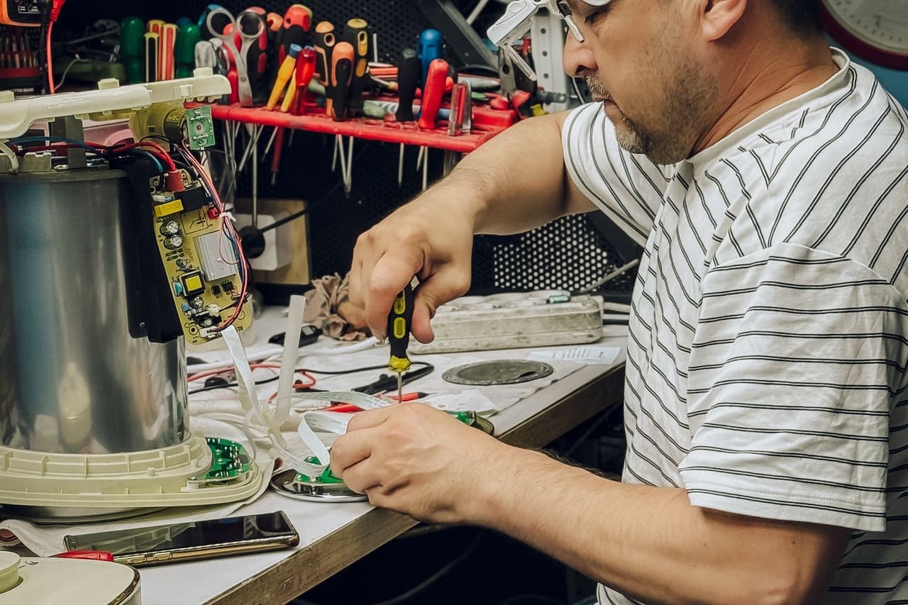 Appliance repair Hayward CA: Electrician repairing device in workshop setting