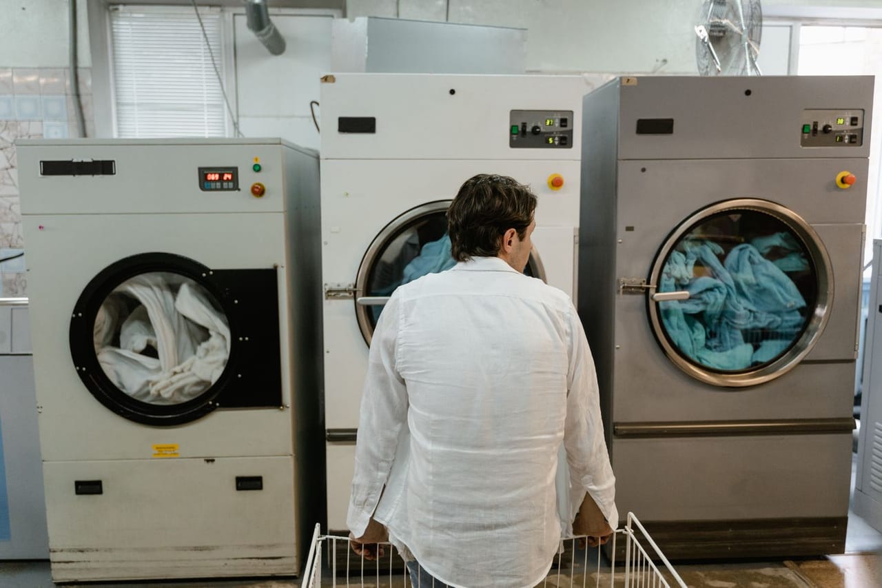 Appliance repair Long Beach CA: A man in white long sleeves sitting beside the washing machine