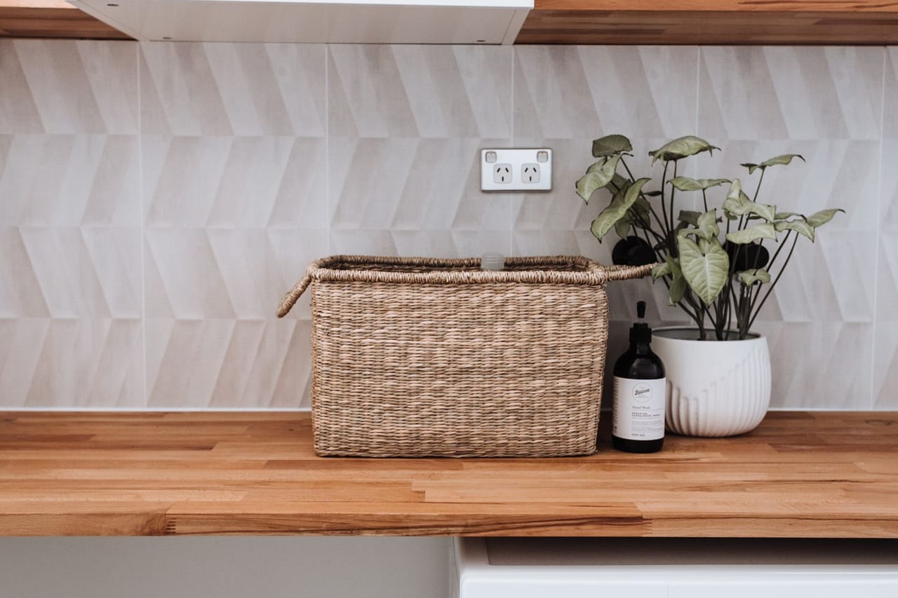 Appliance repair Los Angeles CA: Washing machine under wooden table with plant and wicker basket