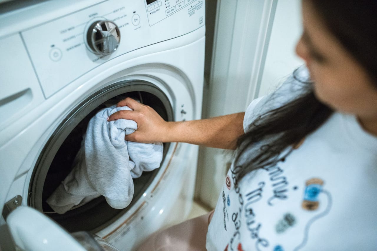 Appliance repair Naperville IL: A woman wearing a white shirt doing a laundry using a washing machine