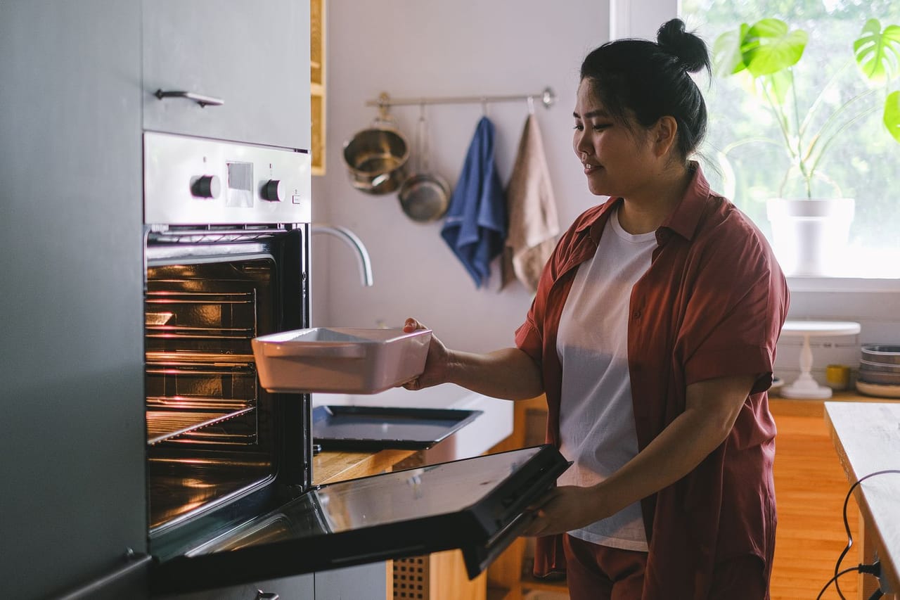 Appliance repair Quad Cities IA: Woman putting food box in an oven