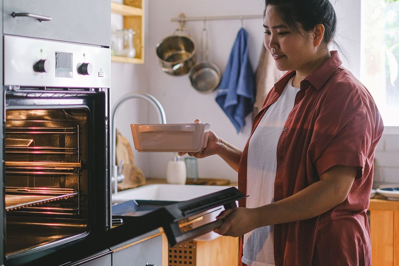 Appliance repair Raleigh NC: Woman putting batter into oven