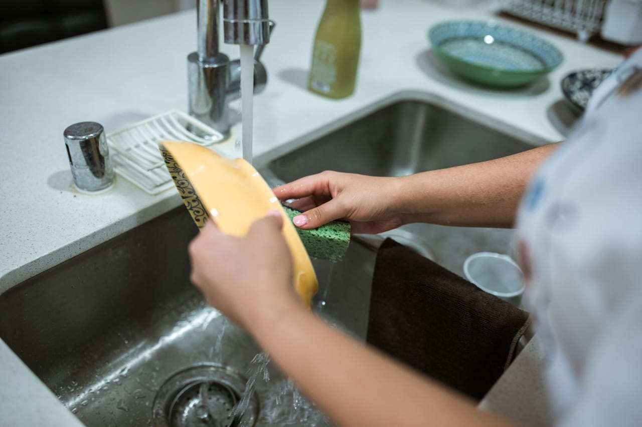 Appliance repair San Diego CA: A person cleaning a yellow bowl using a sponge
