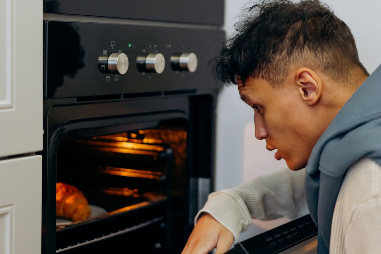 Appliance repair Santa Monica CA: Man in beige sweater sitting in front of a black oven