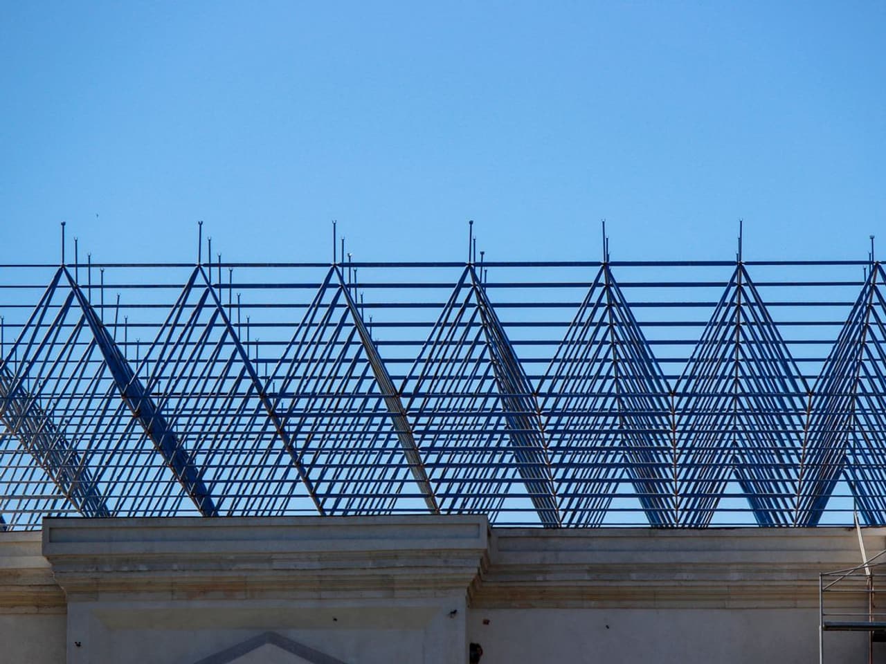 Attic insulation cost: metal roof trusses framing against a blue sky