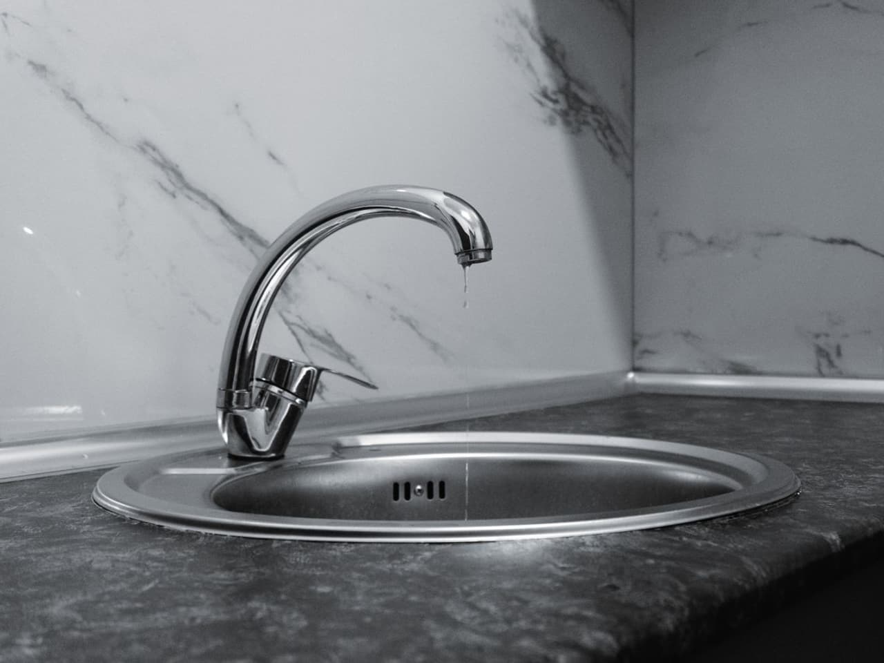 Baking soda and vinegar drain cleaner: chrome faucet above a kitchen sink basin