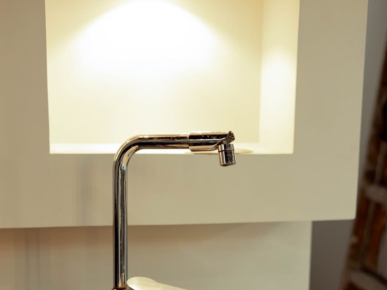 Cleaning a faucet aerator: brass-look faucet spout over a light basin