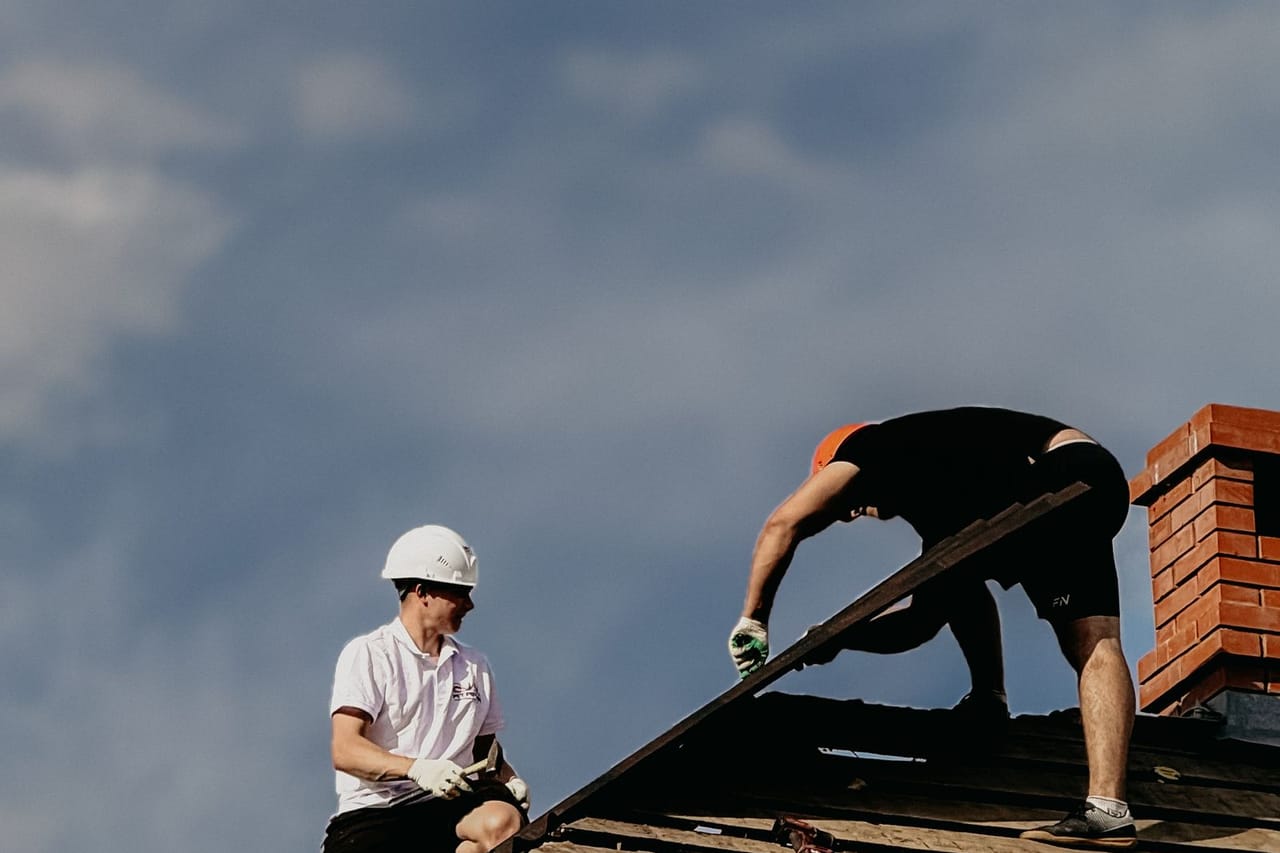 Does home insurance cover a leaking roof: Roofers repairing roof with clear sky background