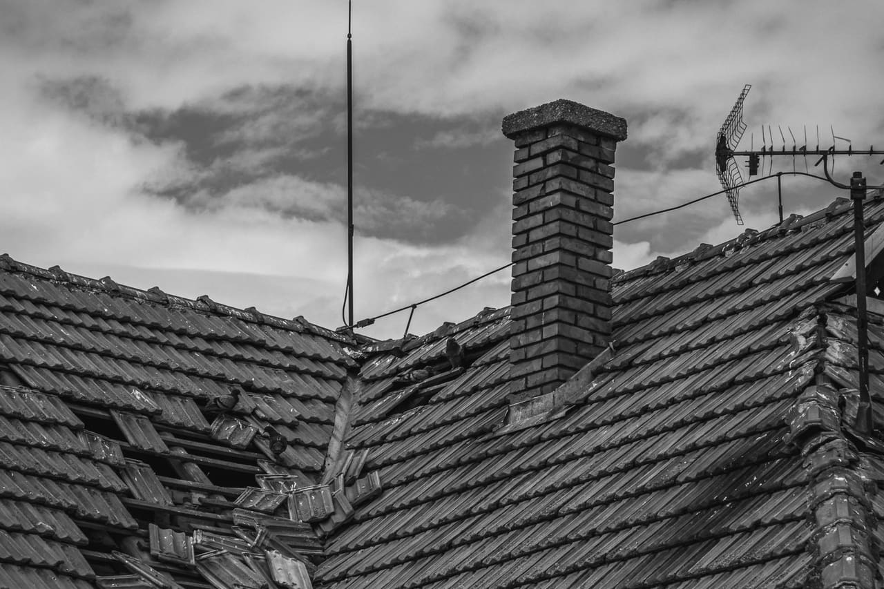 Does homeowners insurance cover ice dam damage: Grayscale photo of a broken roof tiles