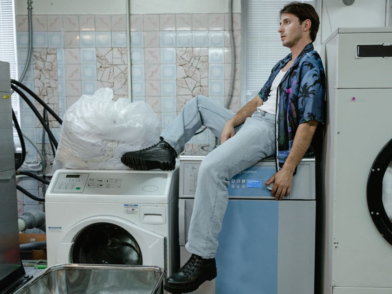 Dryer thermal fuse replacement: man sitting on a dryer beside a washer