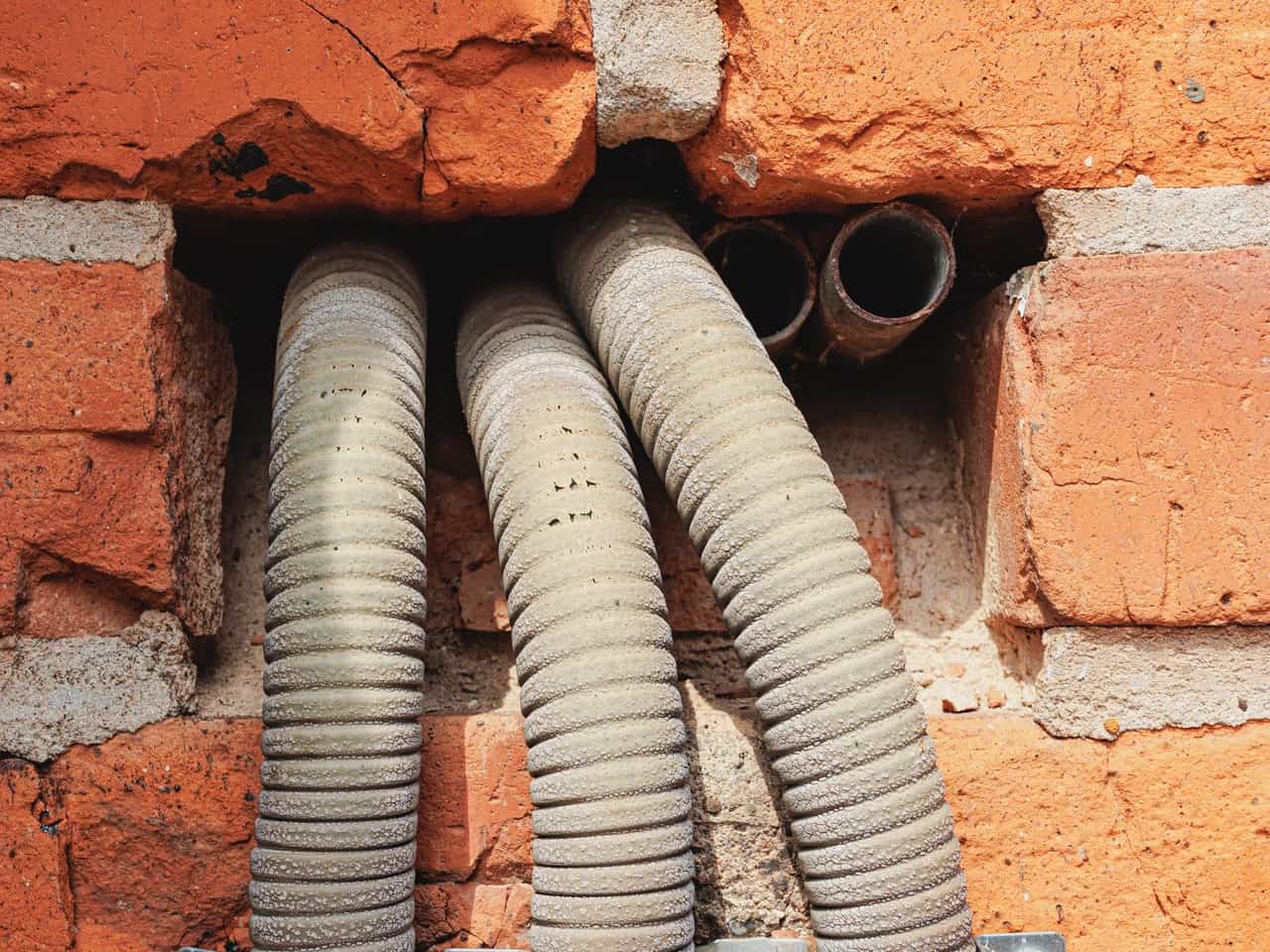 French drain installation cost: corrugated flexible drain pipes running along a brick wall