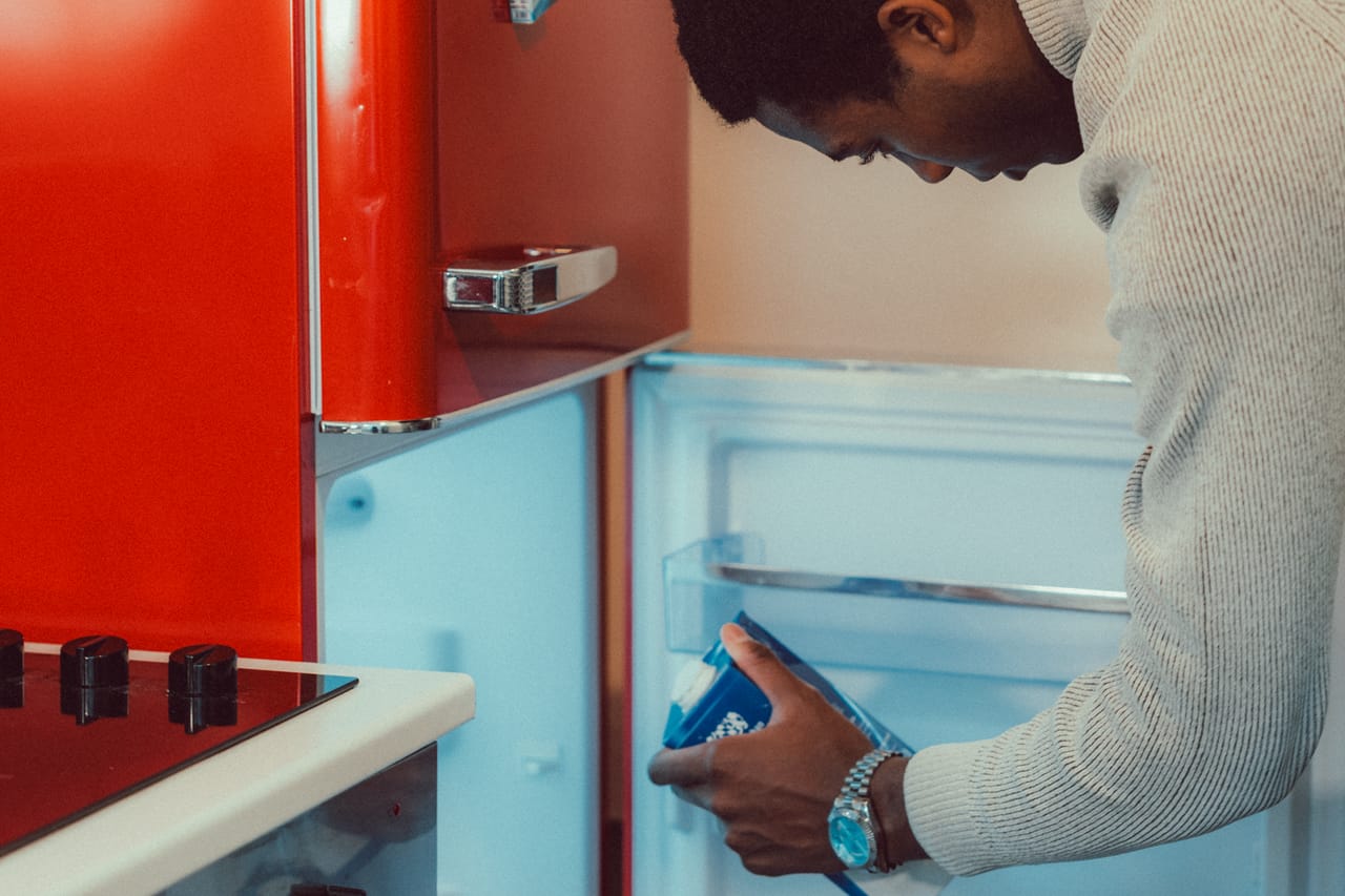 Fridge not cold enough: Man searching fridge for food in modern kitchen