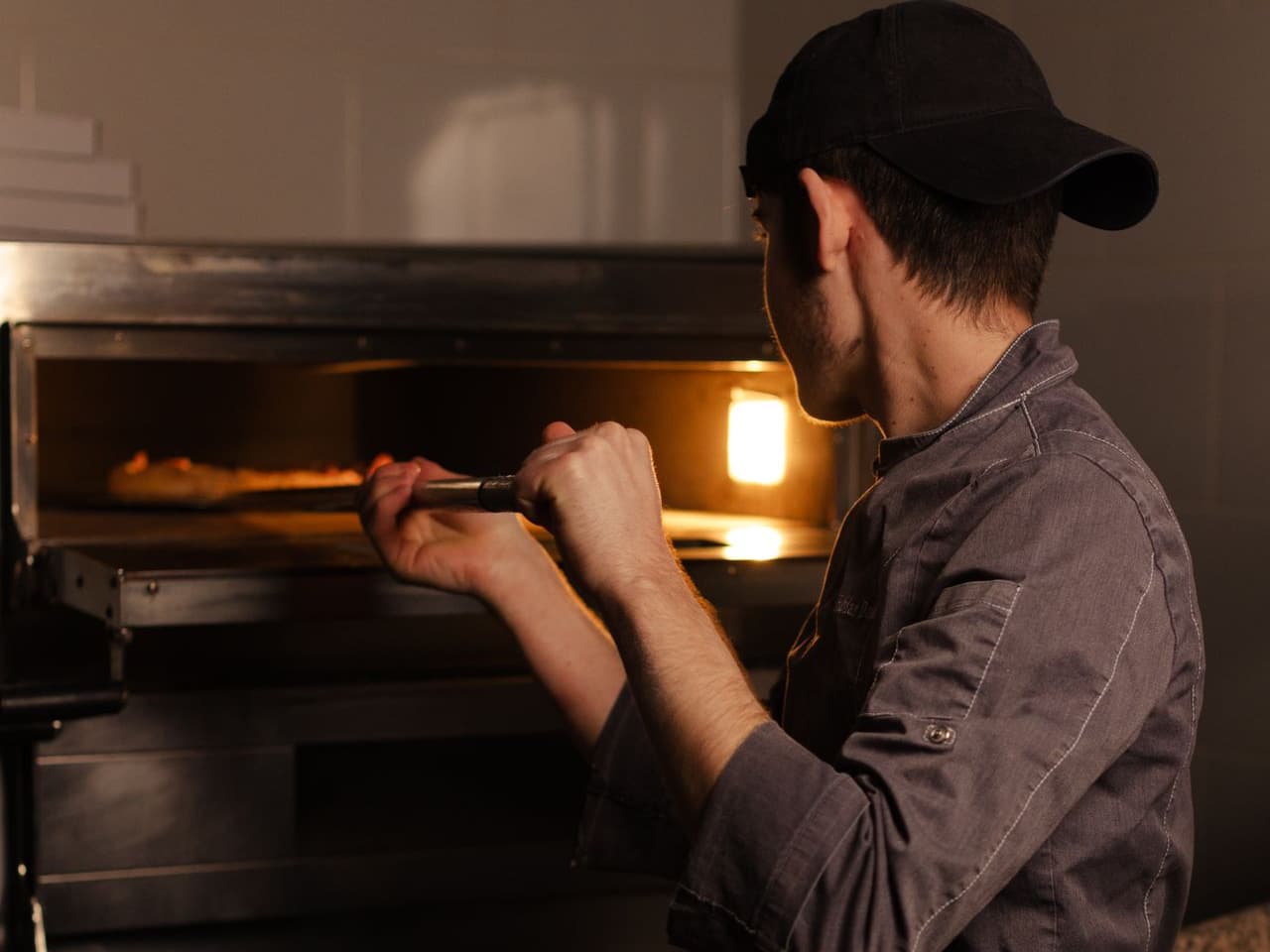 Gas vs electric stove: man working at a built-in oven beside a brick wall