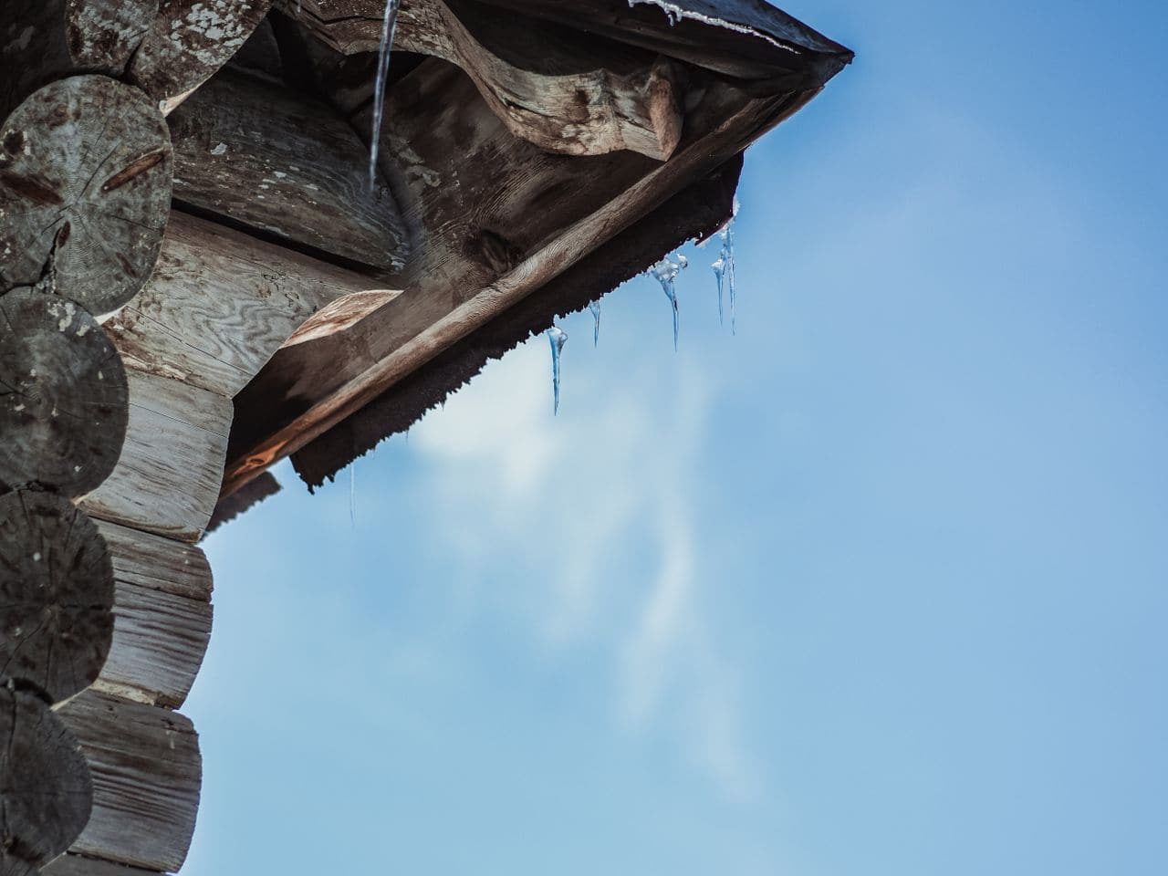 Gutter cleaning cost: bent metal roof edge against a pale sky