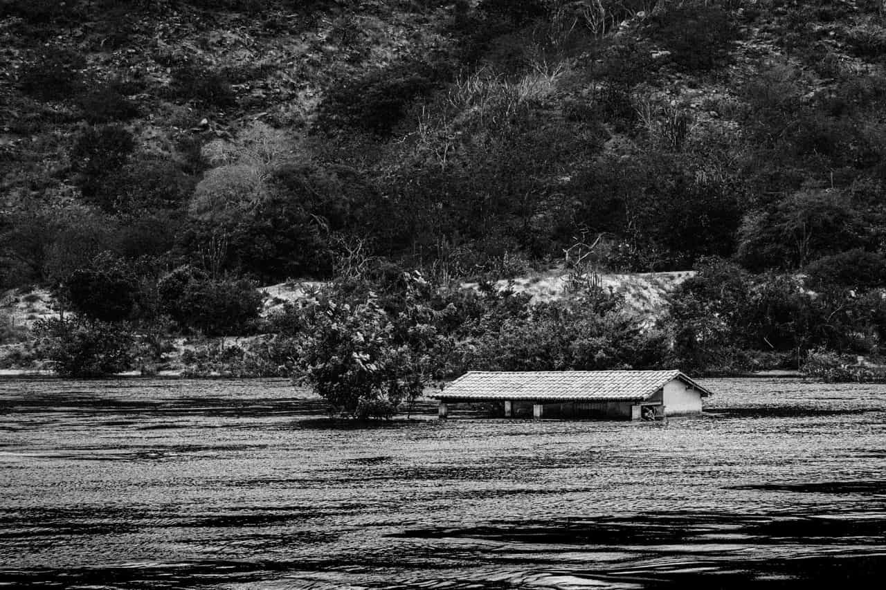 Home insurance water damage: A grayscale photo of house on body of water