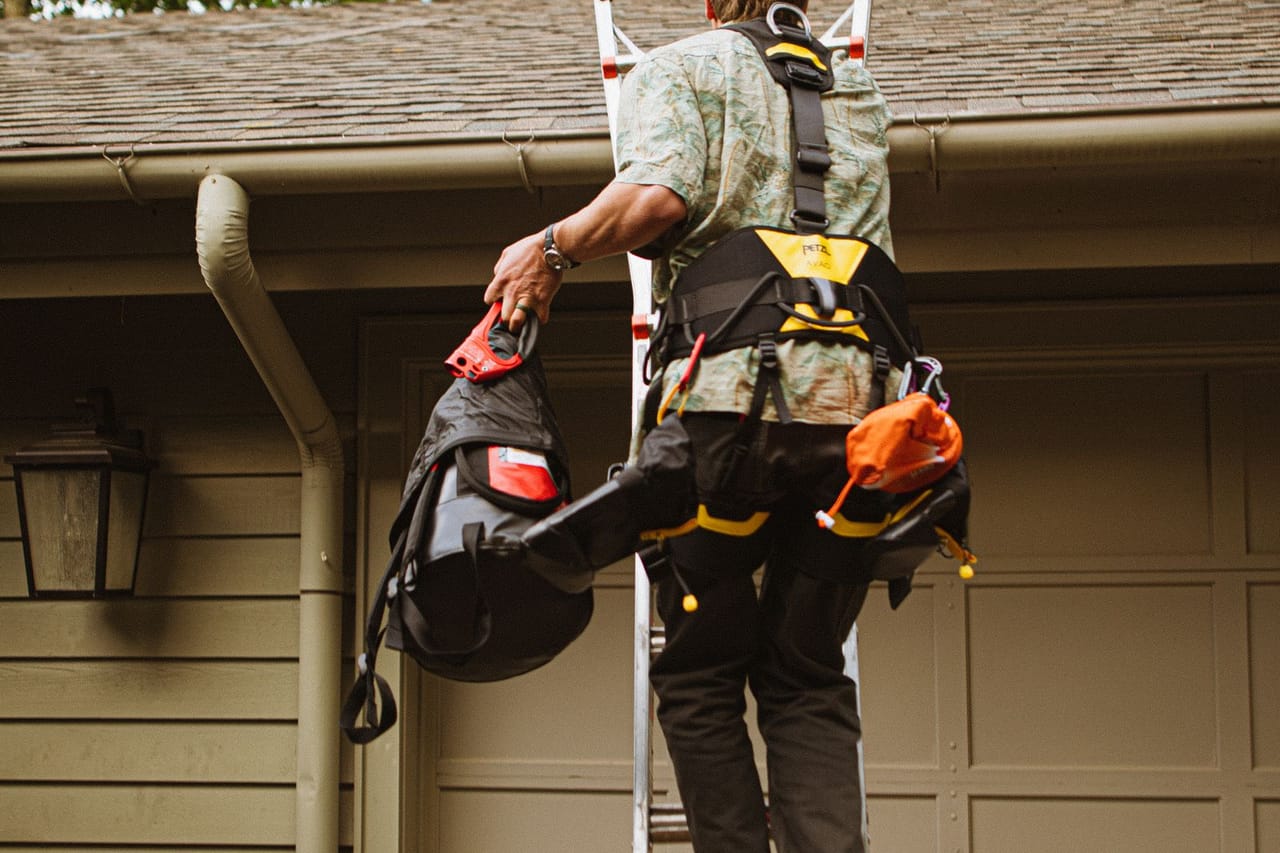 How do you repair a leaking roof: Skilled roofer climbing ladder for roof repair