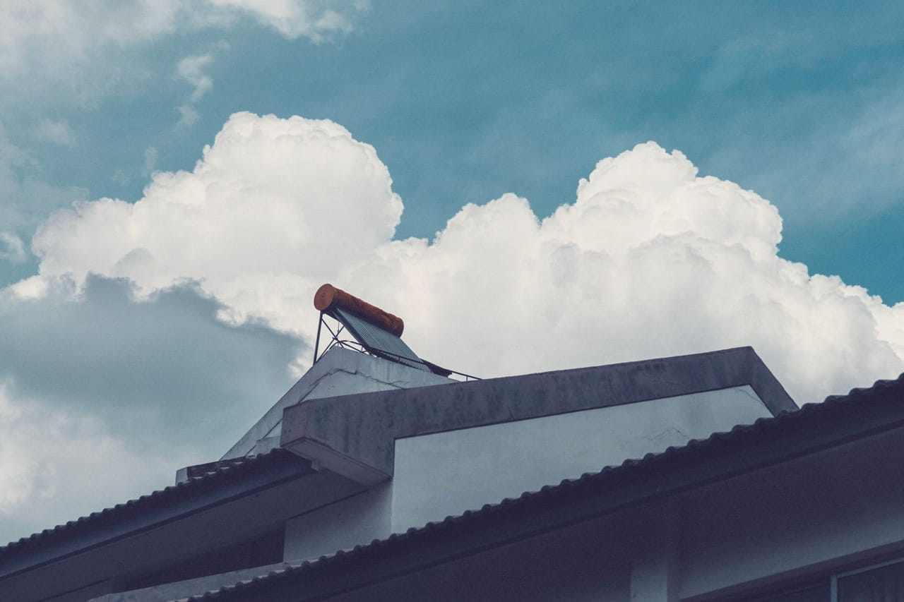 How long does a water heater last: Solar water heater on rooftop against cloudy sky