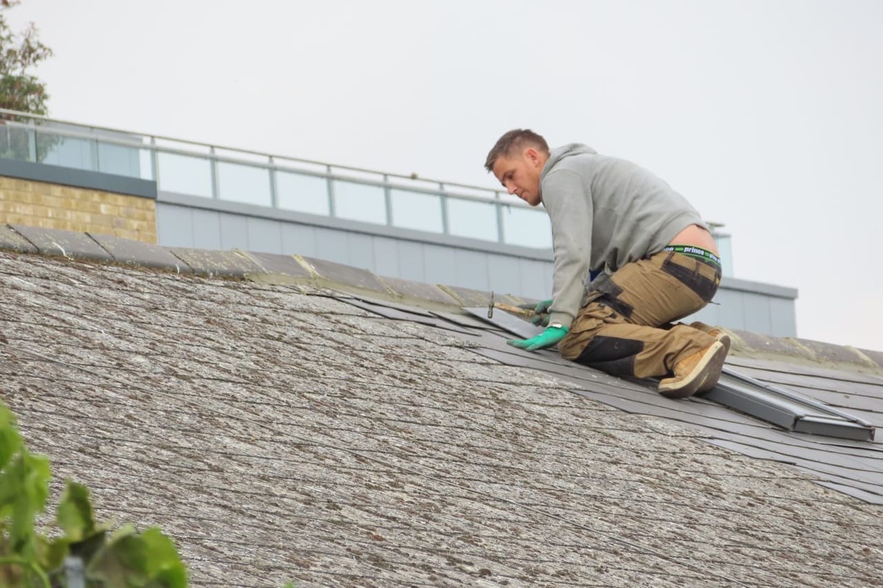 How much does a roof inspection cost: Handyman putting roof tiles on roof