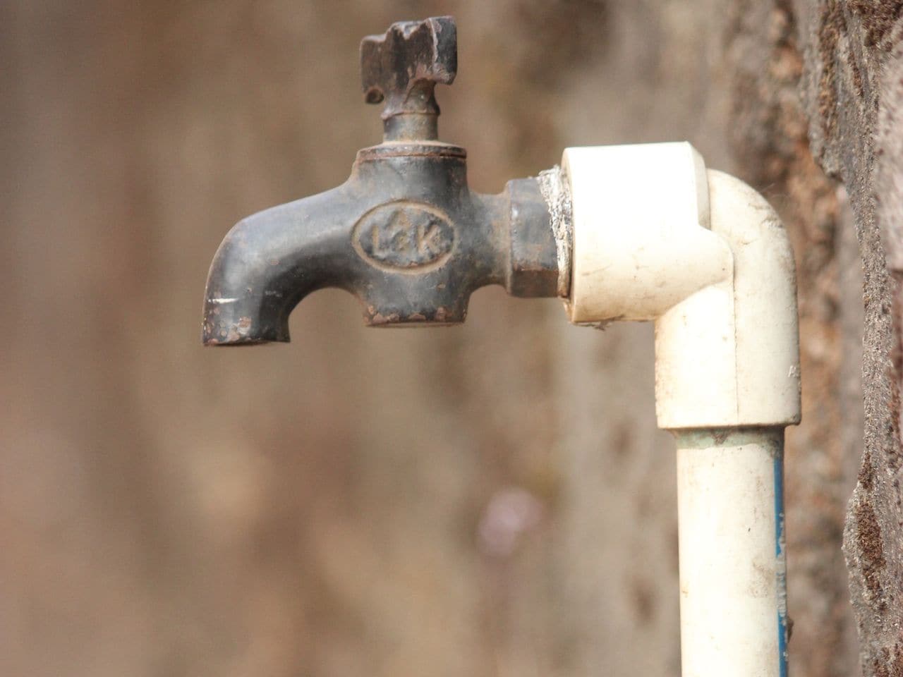 How to cut pvc pipe: white plastic pipe rising from a wall beside a tap