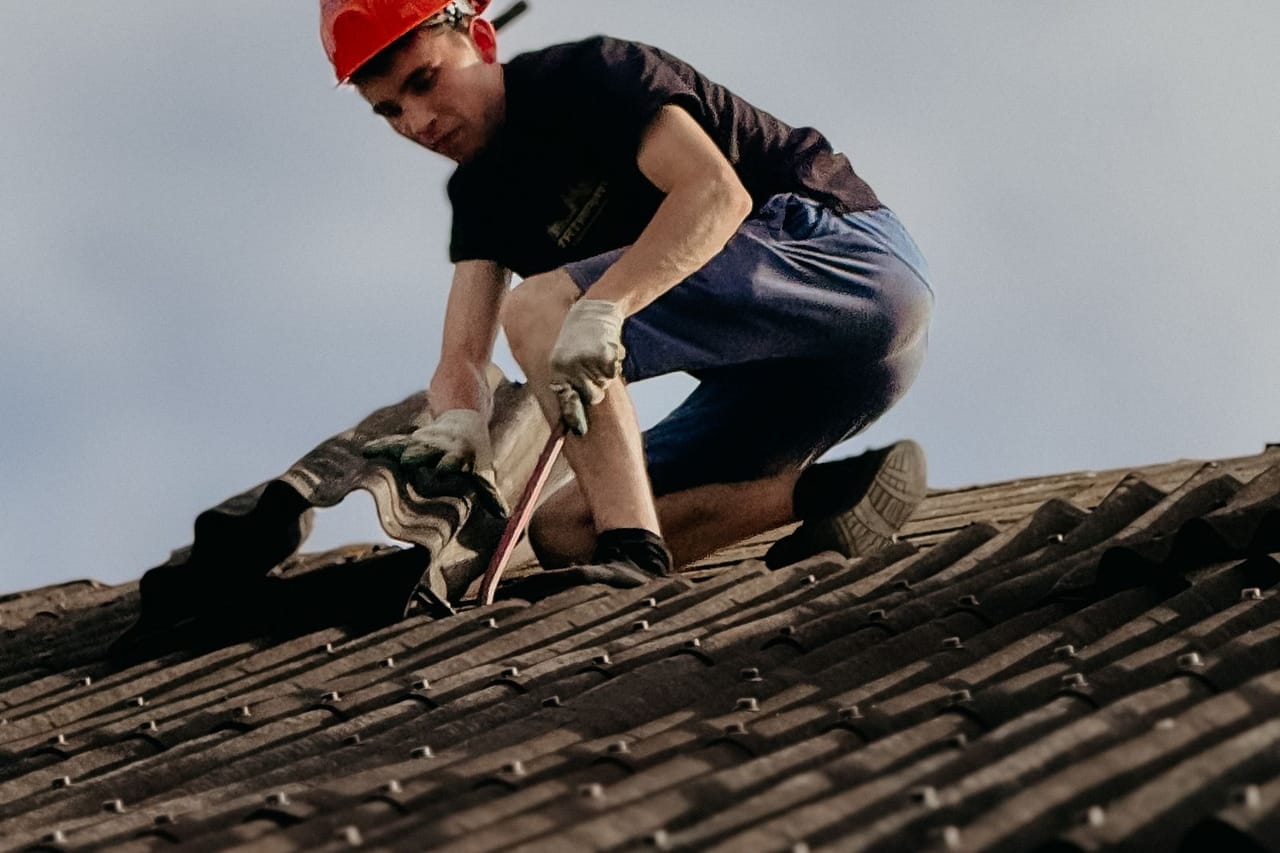 How to find where a roof is leaking: Construction worker repairing roof in daylight