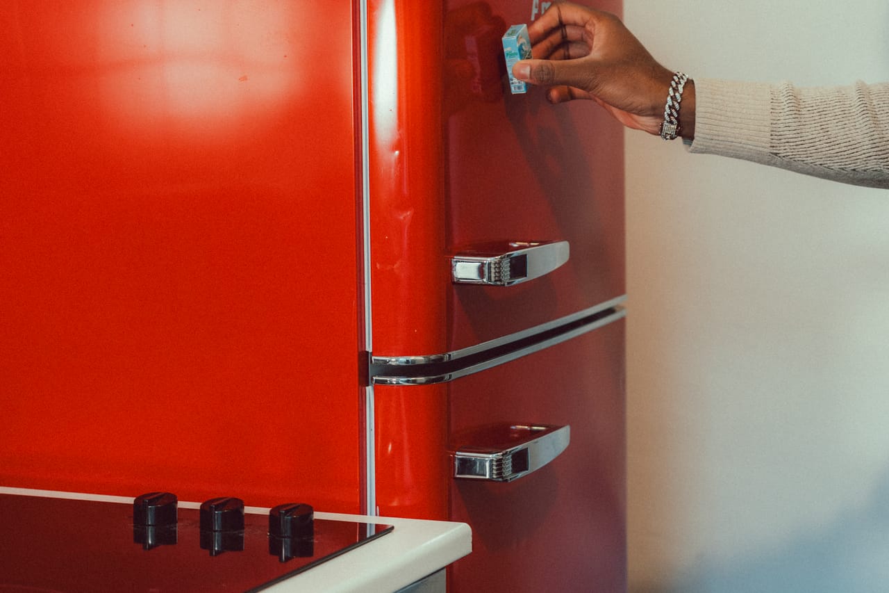 How to fix refrigerator not cooling: Hand reaching for retro red refrigerator handle
