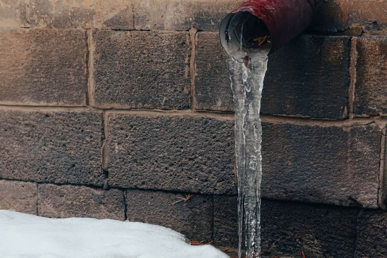 How to know if a pipe burst: Frozen water pipe drips ice in urban winter scene