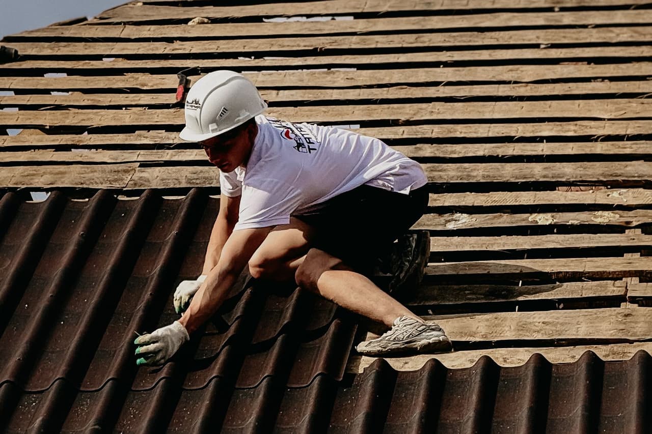 How to measure roof pitch: Roofer working on roof installation with safety gear