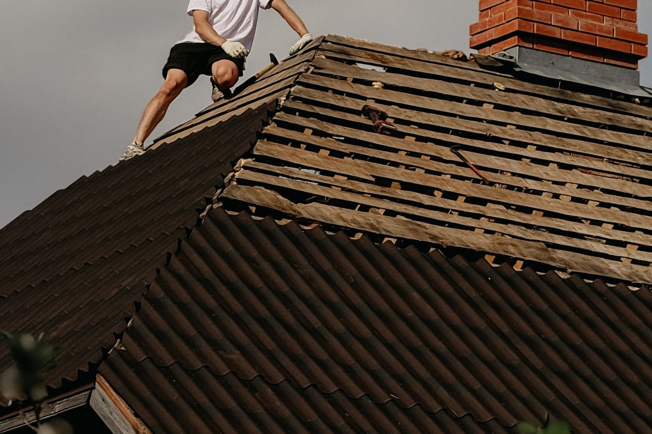 How to tarp a roof: Worker on roof conducting repairs on sunny day
