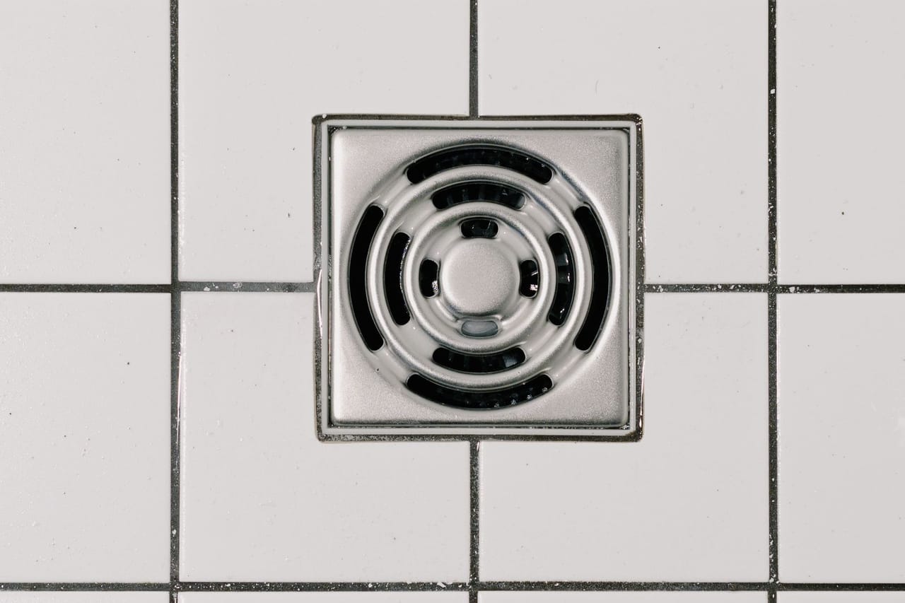 How to unclog a bathtub drain: Stainless steel cover of drain in modern shower