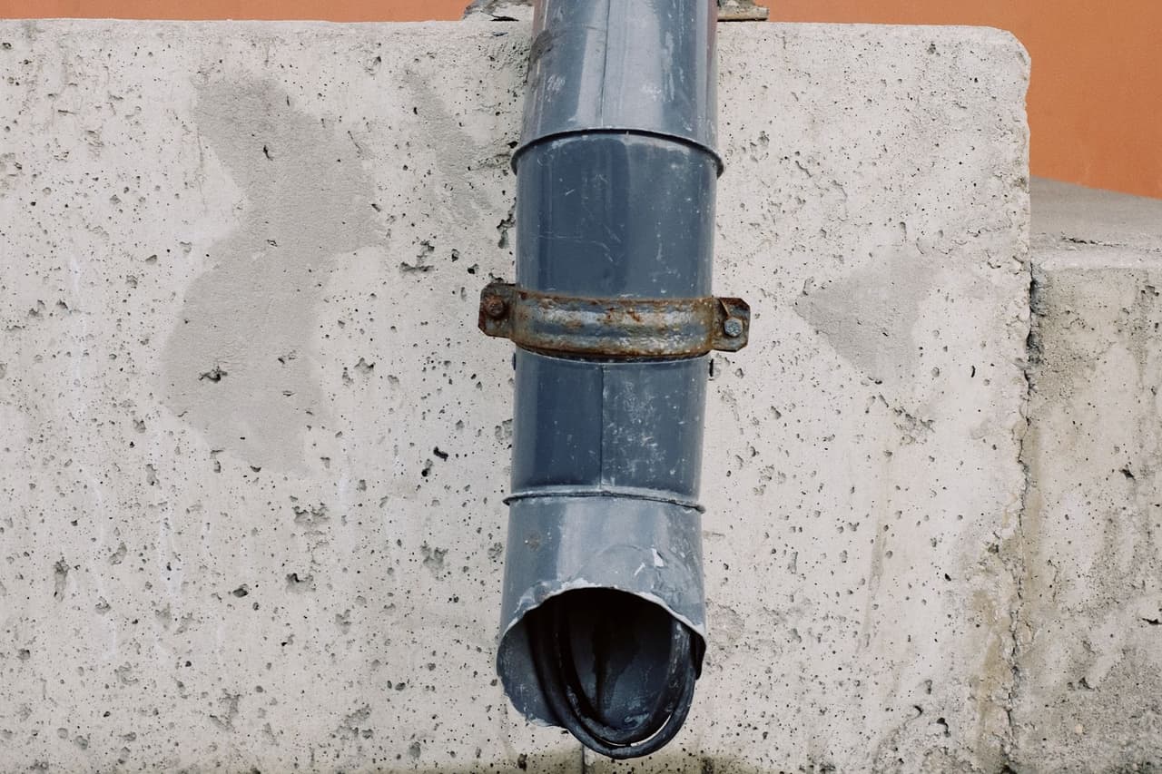 How to unclog a house drain: House drain pipe on concrete wall