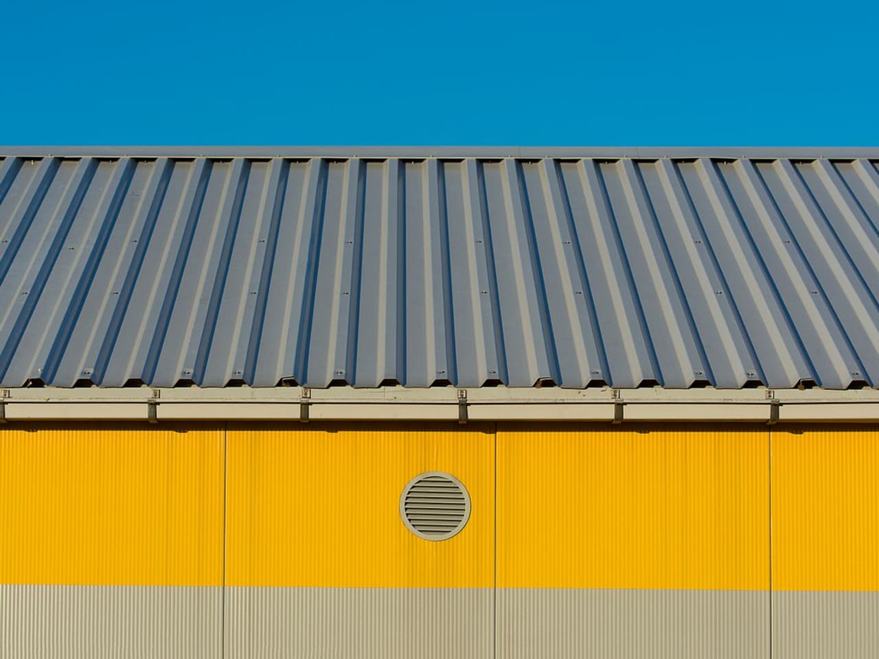 Metal roof installation cost: blue corrugated metal roof over a yellow building