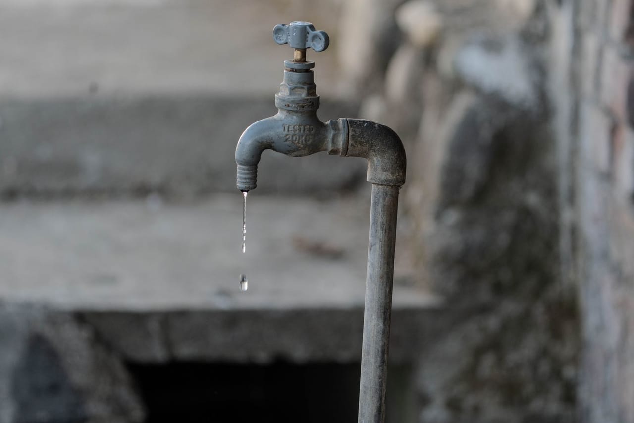 Outdoor faucet leaking: Rustic outdoor water faucet dripping with natural gray tones