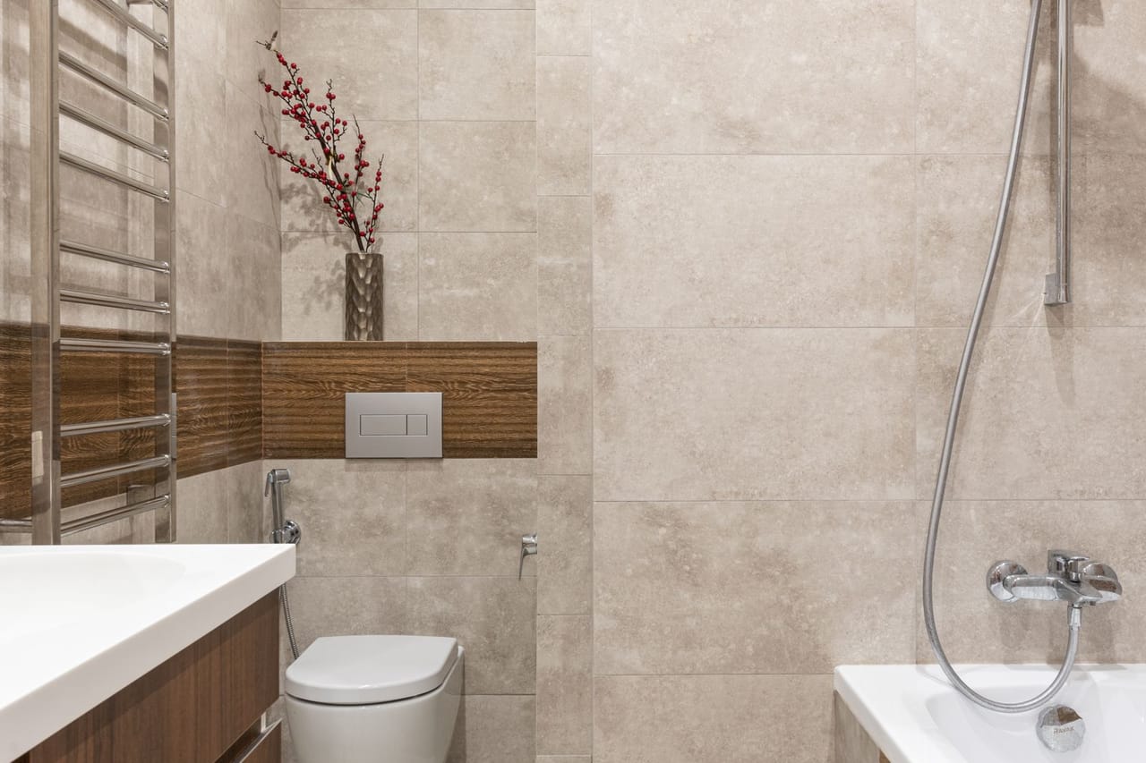 Plumber cost to replace toilet: White ceramic toilet bowl on brown wall tile