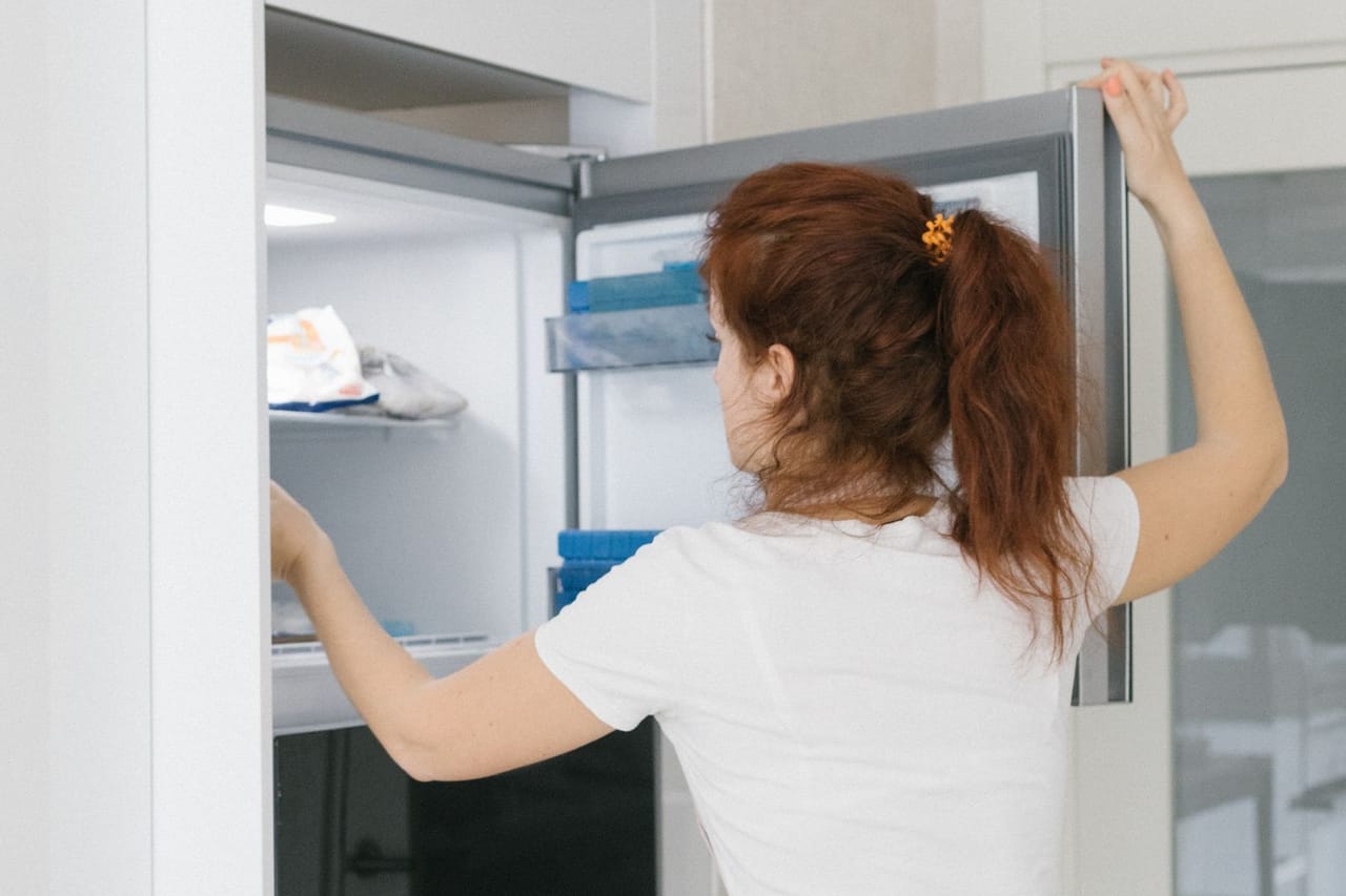 Refrigerator freezing food: A woman opening a refrigerator