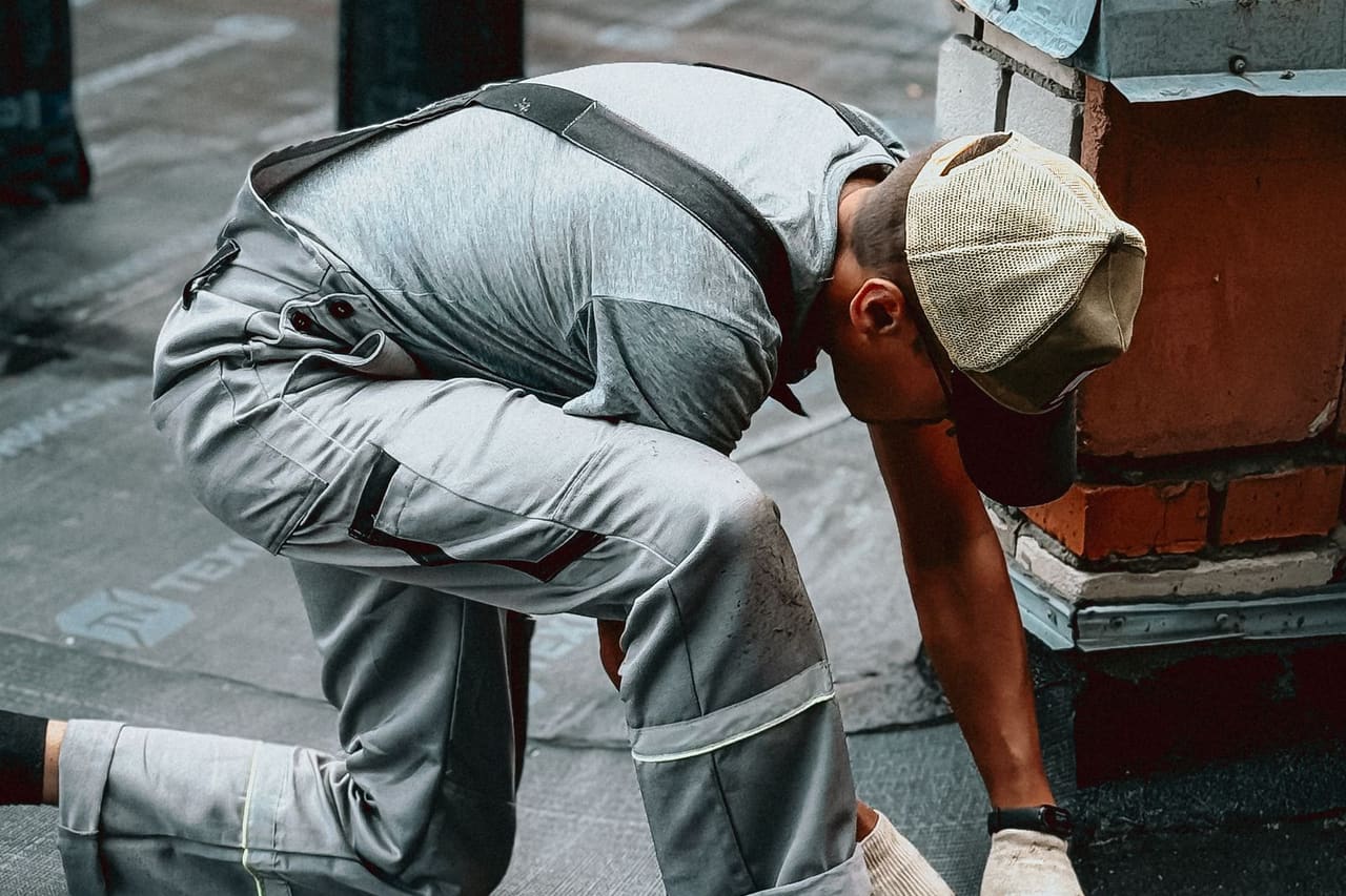 Roof repair leak cost: Roofer working on urban roof during daytime