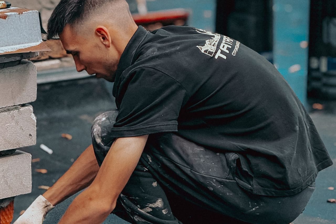 Roof replacement cost estimator: Young construction worker laying roof tiles