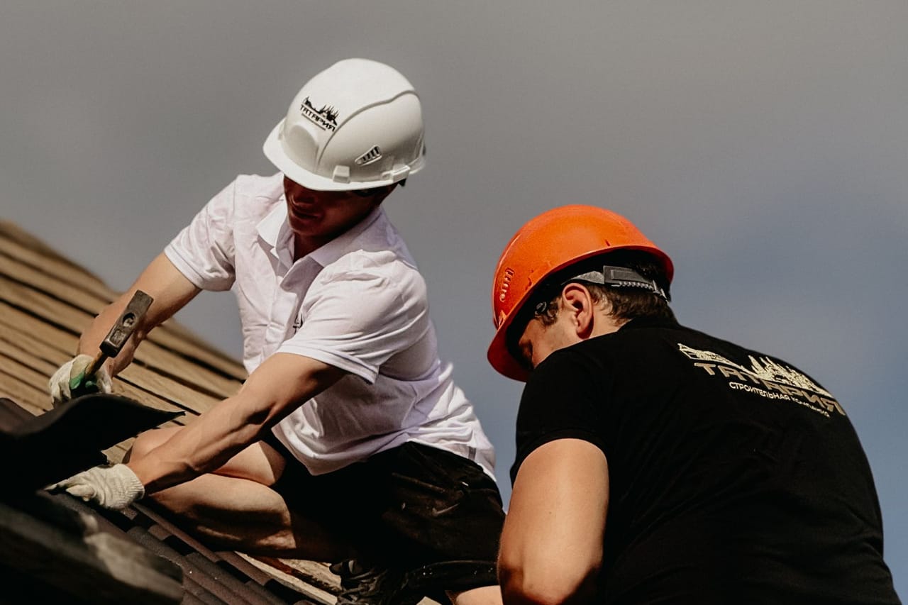 Roof replacement cost per sq ft: Roof construction workers at a building site