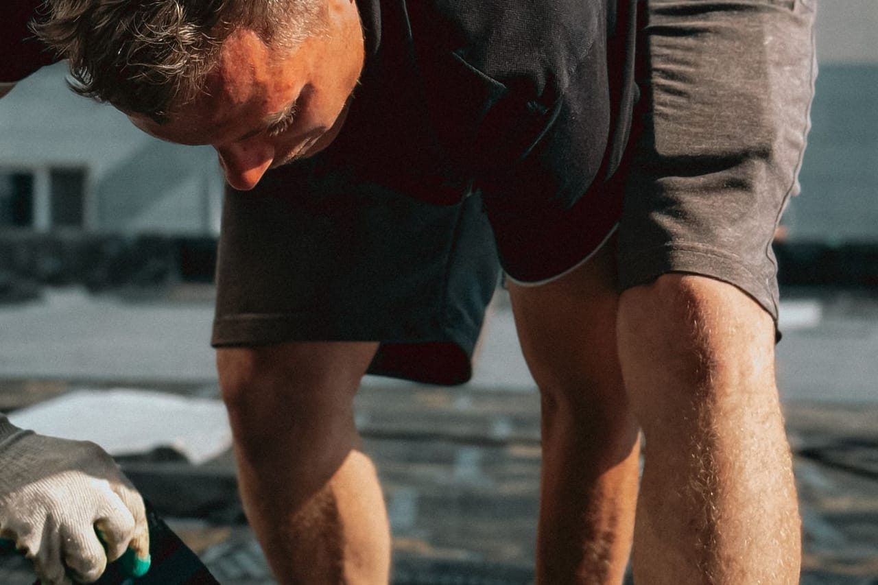 Shingles curling: Construction worker laying asphalt shingles