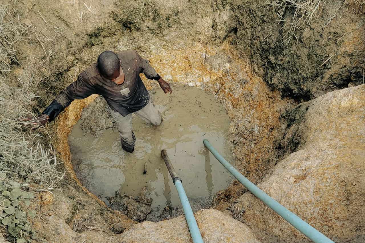 Sump pump not working: Man working in muddy excavation site with pipes