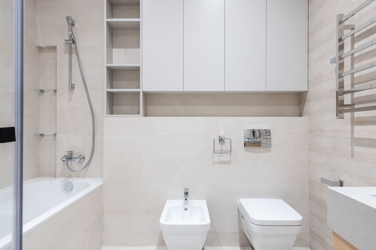 Toilet leaking at base: Bathroom with toilet and bidet near bathtub and sink