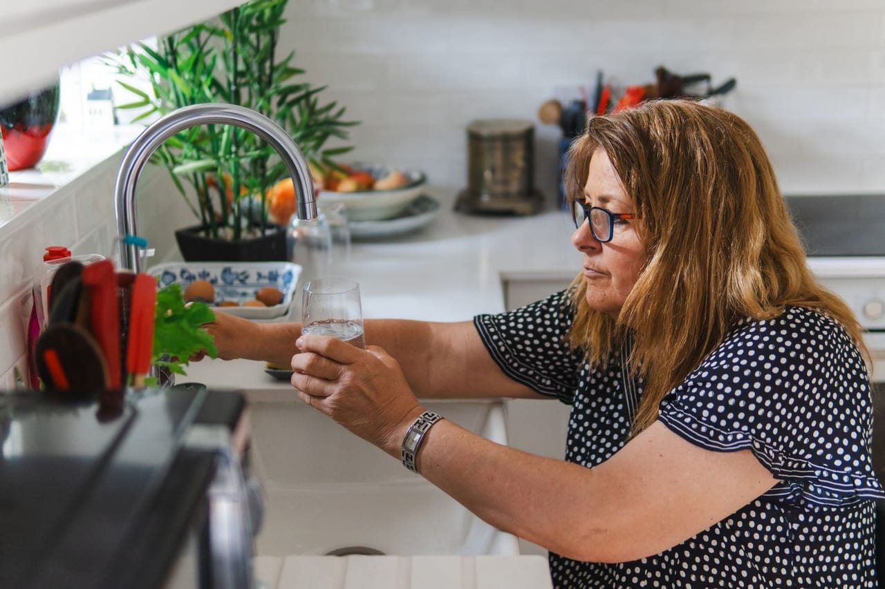Toilet not filling with water: Woman filling glass with water in home kitchen