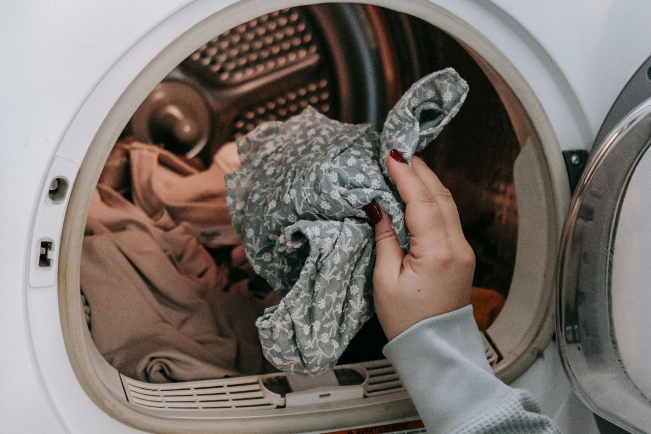 Washing machine is not draining: Anonymous woman putting clothes in washing machine