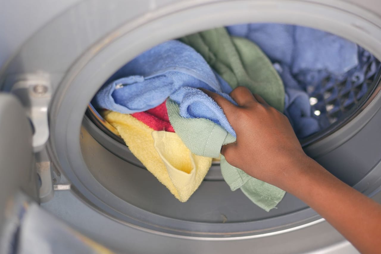 Washing machine repair cost: Woman hand putting towels in washing machine