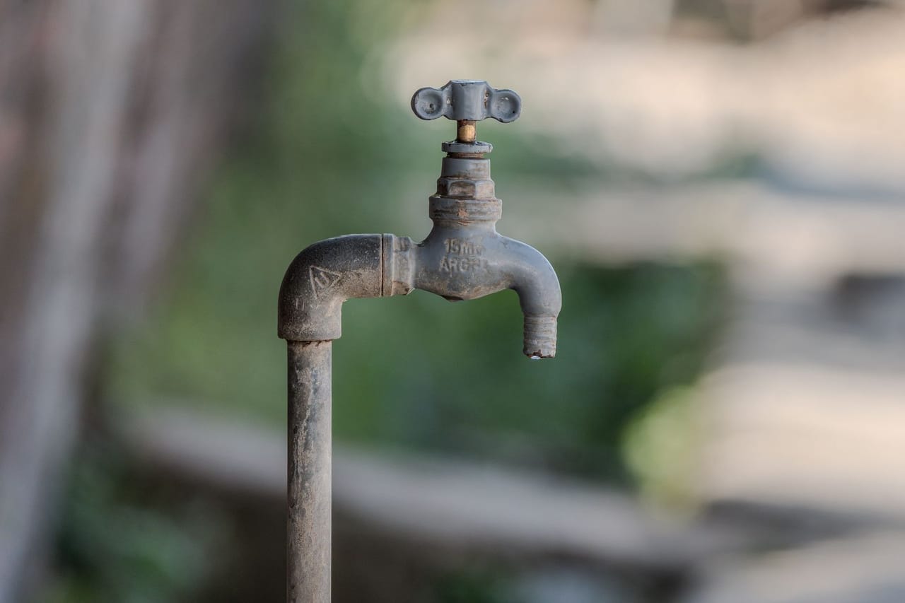 Water heater replacement cost: Rustic outdoor water faucet with blurred background