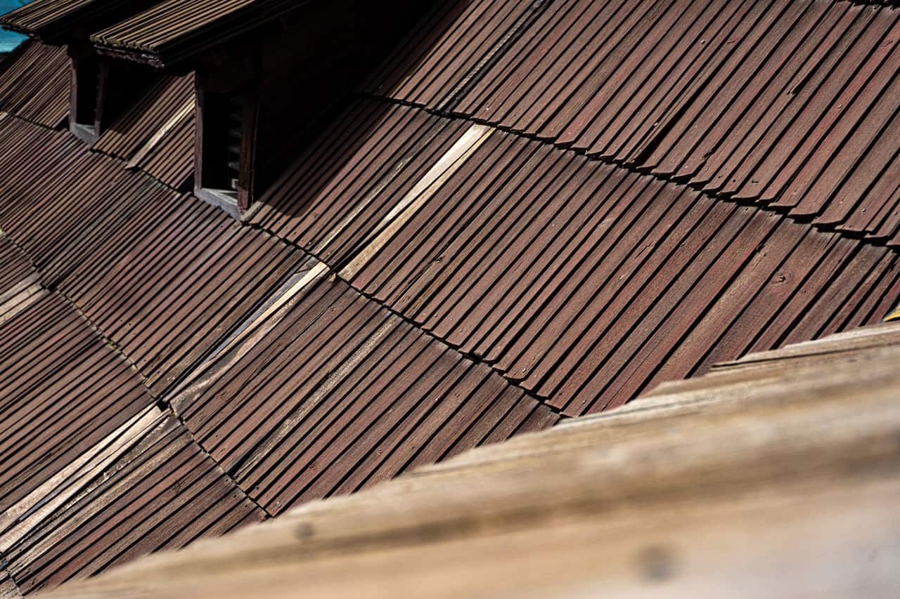 What does hail damage look like on shingles: Close up of rustic wooden roof shingles