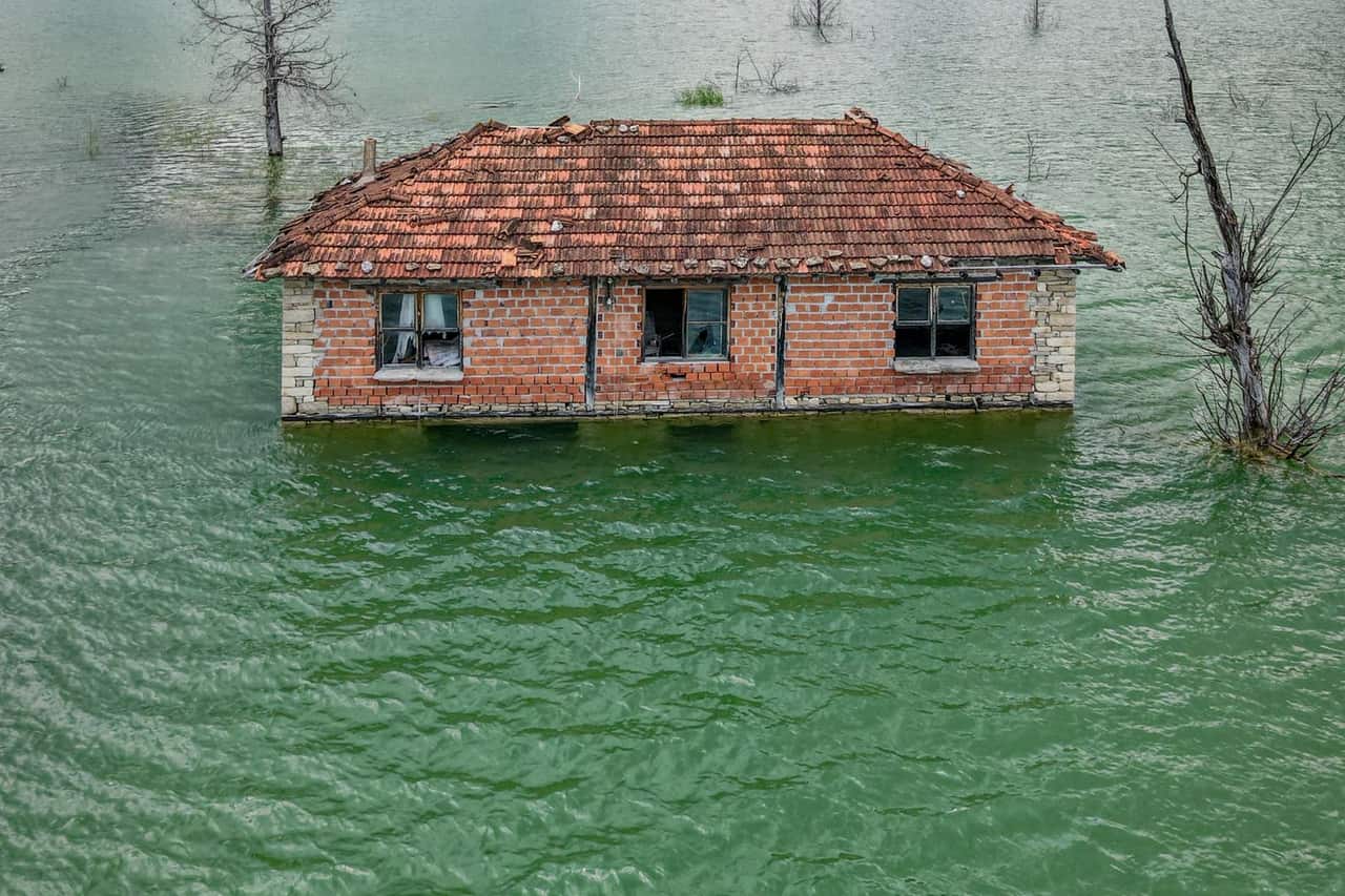 What to do for flooded basement: A flooded house in the middle of a lake in a mountain valley
