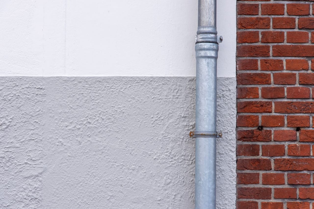 Plumber Des Moines IA: Exterior brick wall with metal drainpipe