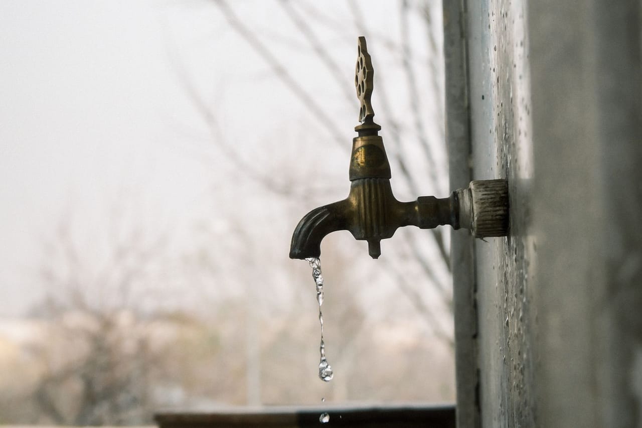 Plumber Kennesaw GA: Dripping outdoor water faucet in urban setting