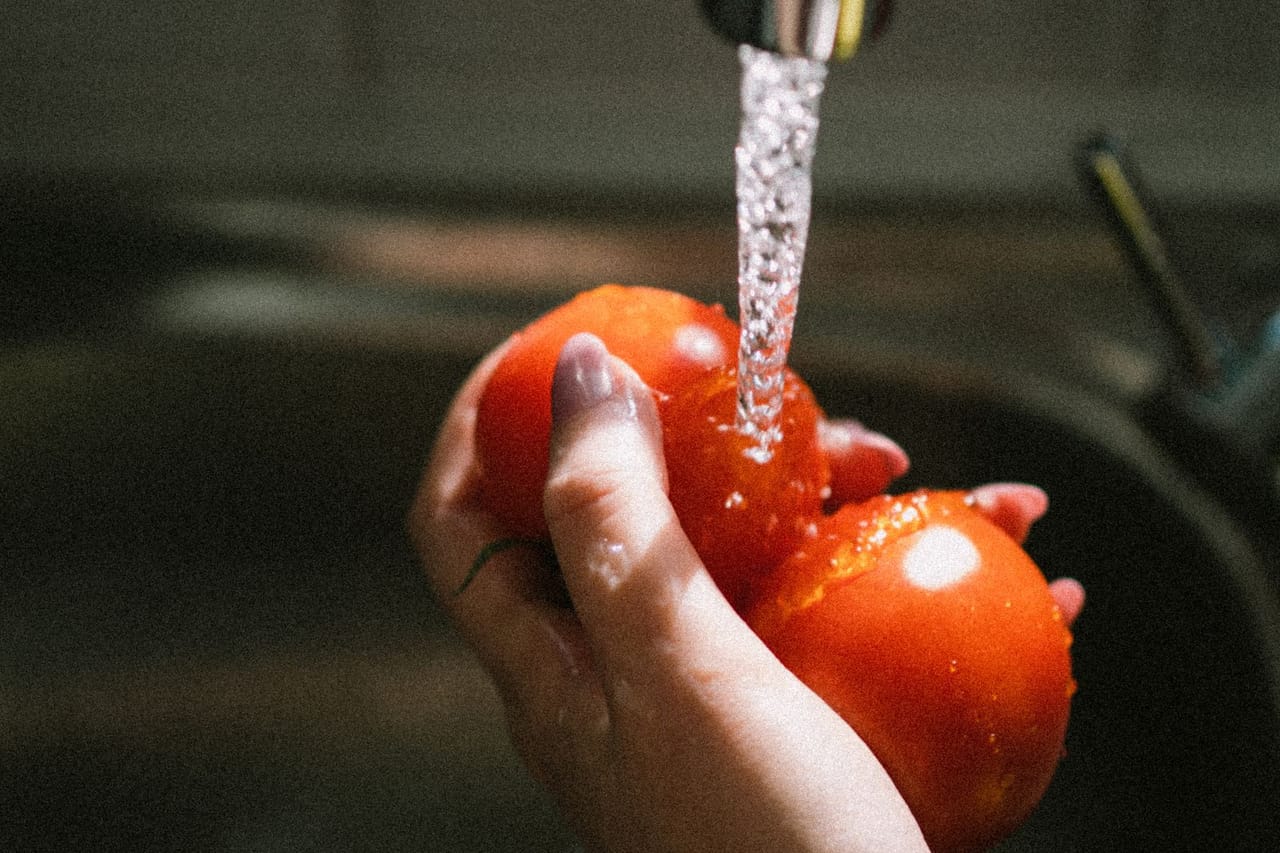 Plumber Miami FL: Woman hand washing tomatoes under tap water
